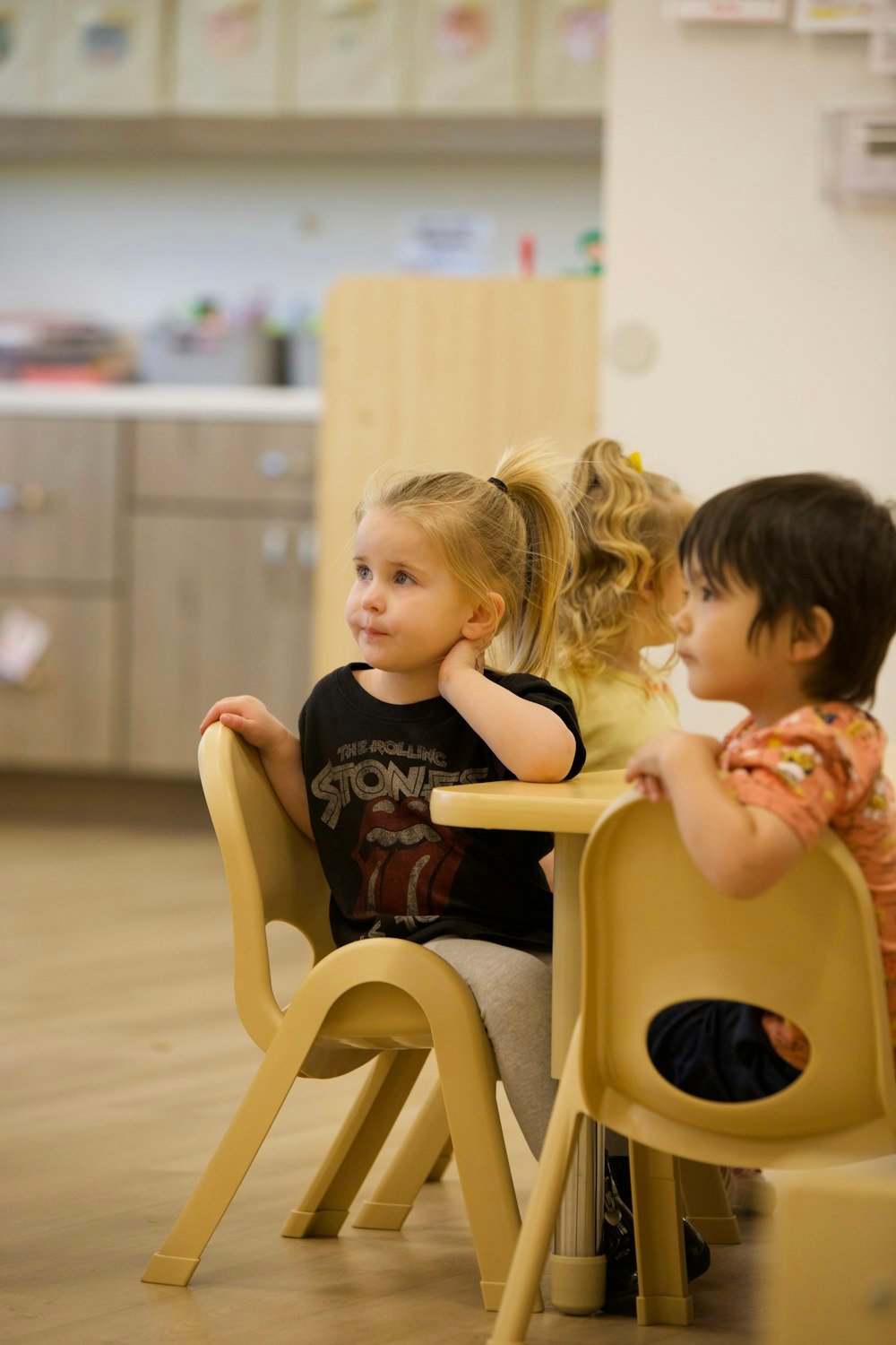 Niños sentados en la sala escuchando a su educadora
